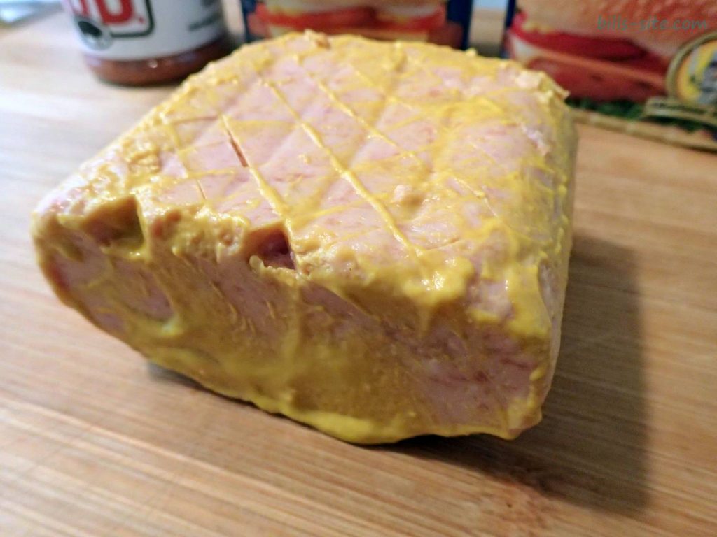 applying yellow mustard to help hold the barbecue rub